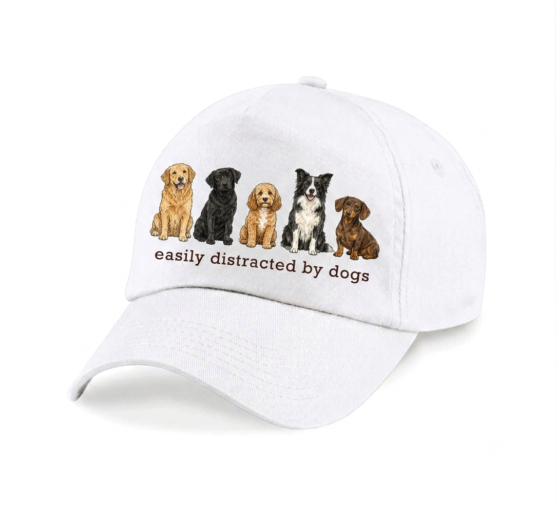 A white baseball cap featuring an DTF graphic of five different dog breeds sitting in a row, with the text 'easily distracted by dogs' printed underneath.