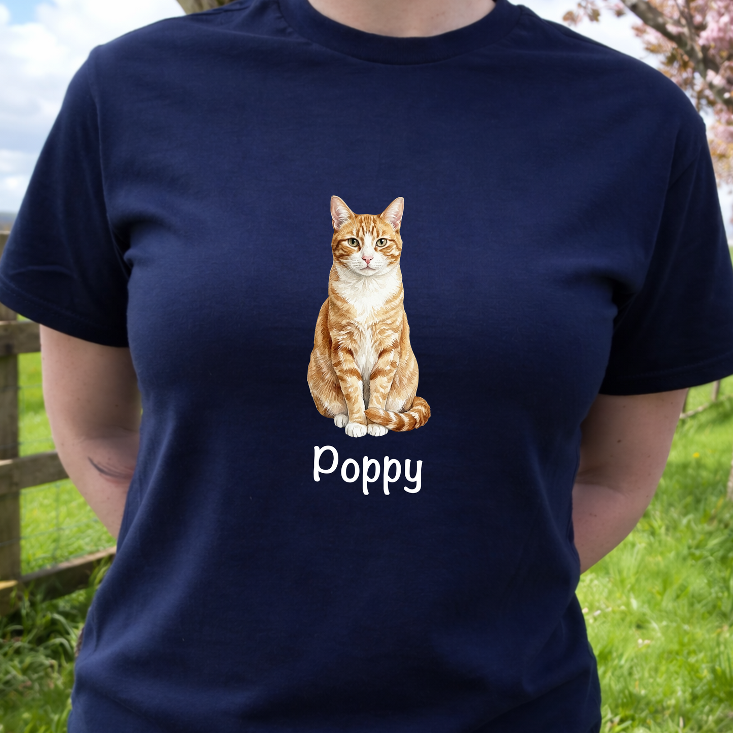 Person wearing a navy blue t-shirt with a cat illustration and 'Poppy' text, standing outdoors.