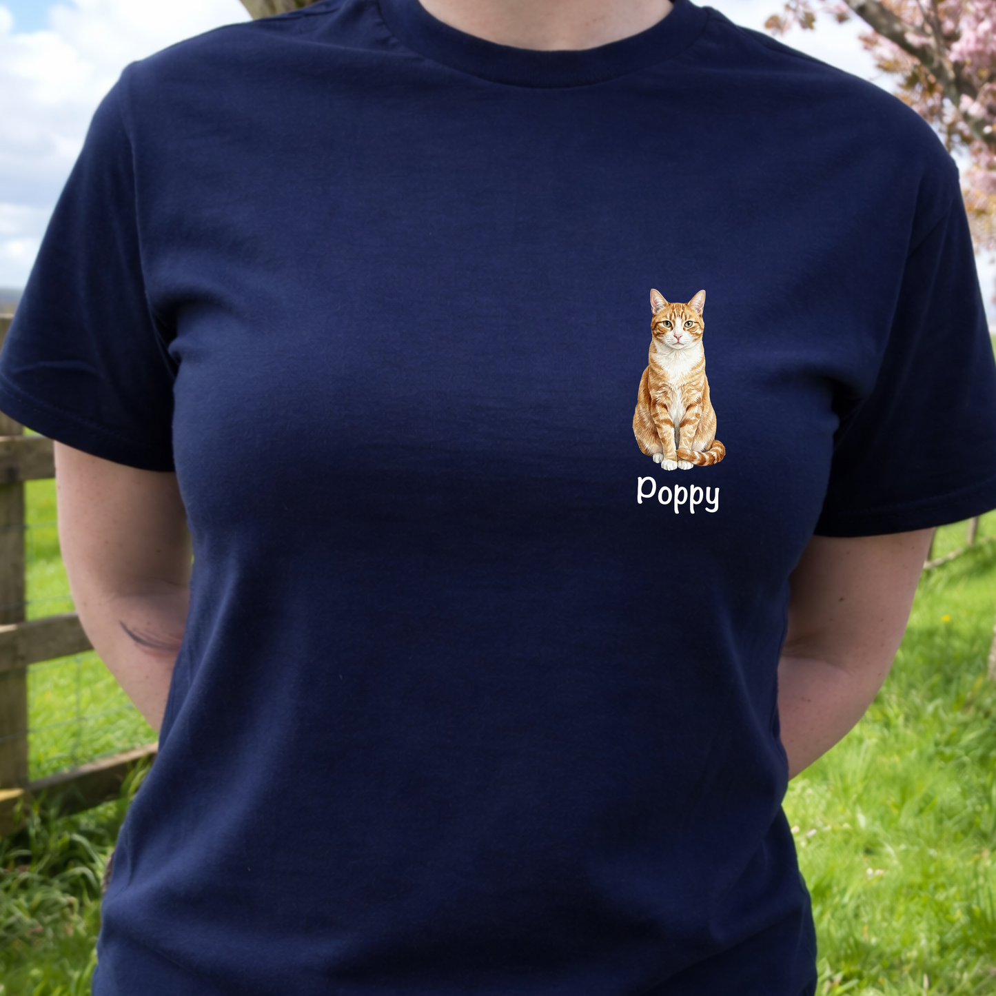 Person wearing a navy blue t-shirt with a cat illustration and 'Poppy' text, standing outdoors.