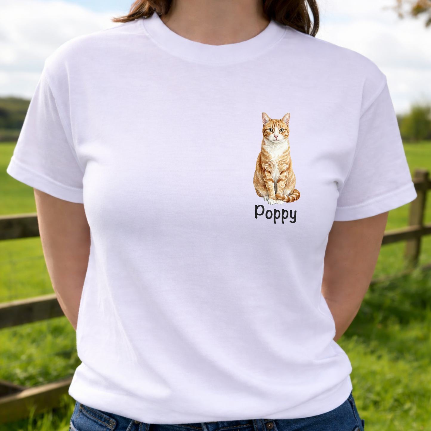 Person wearing a white t-shirt with a cat illustration and 'Poppy' text, standing outdoors.